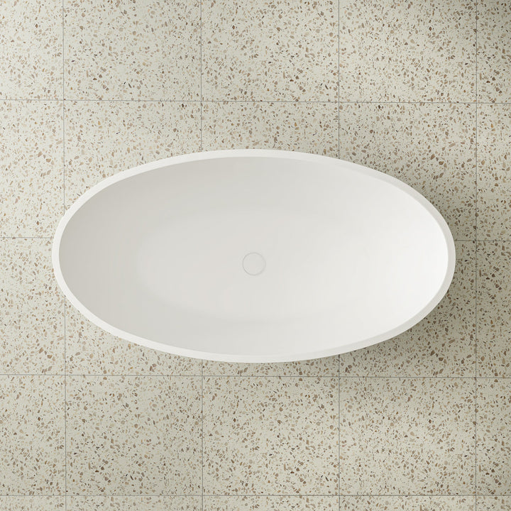 Top view of a white oval artificial stone bathtub elegantly placed on a stylish tiled floor.