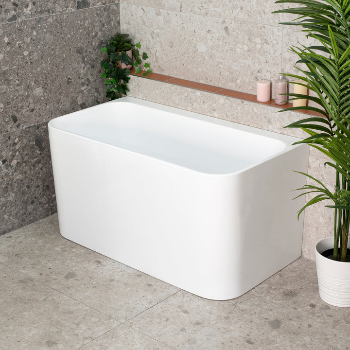 Estus Back to Wall Bathtub with Seat in matte white with deep soaking design and rounded edges in a modern bathroom interior.
