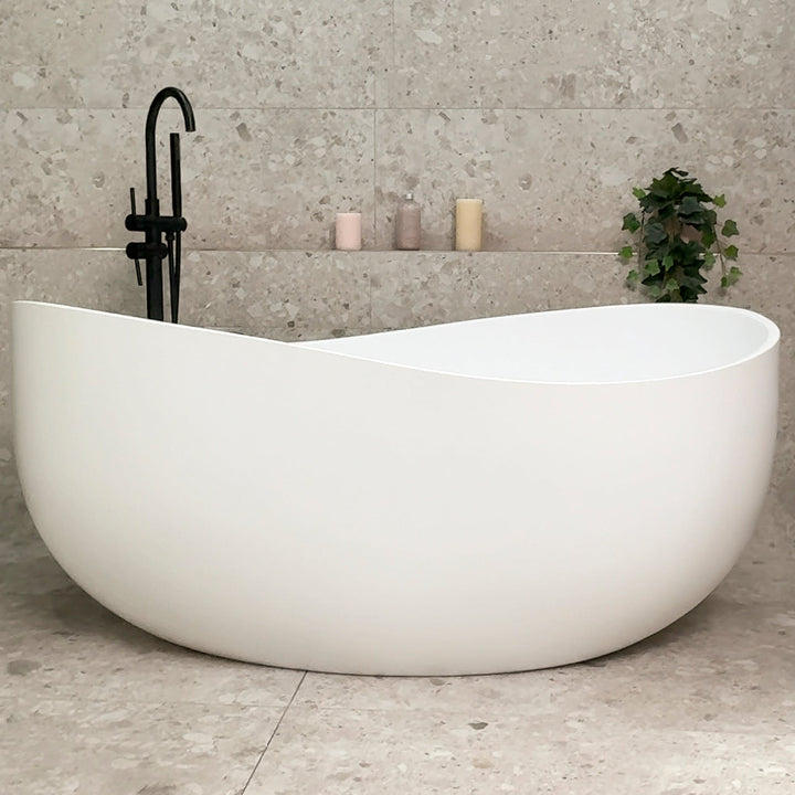 Wave Oval Wide freestanding bathtub in matte white with floor-mounted bath filler in modern stone-look bathroom