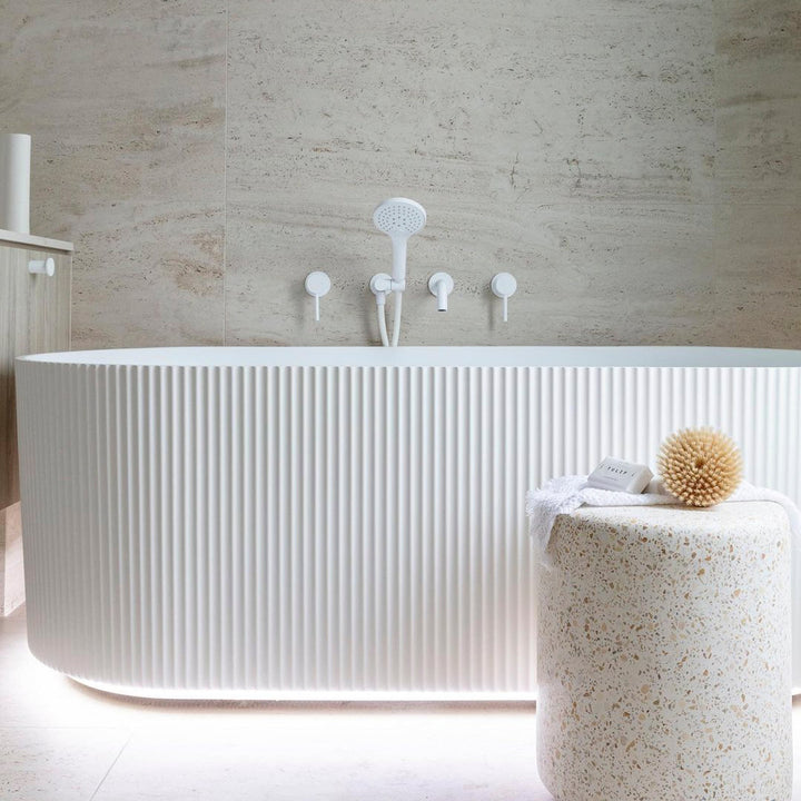 Brighton Groove Fluted Acrylic Bathtub with ribbed matte white exterior in a modern bathroom with travertine-look wall tiles.