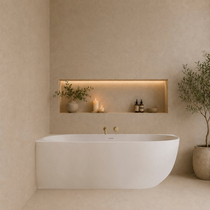 Corner freestanding bathtub in a modern neutral bathroom with brushed brass wall-mounted tapware and recessed shelf lighting
