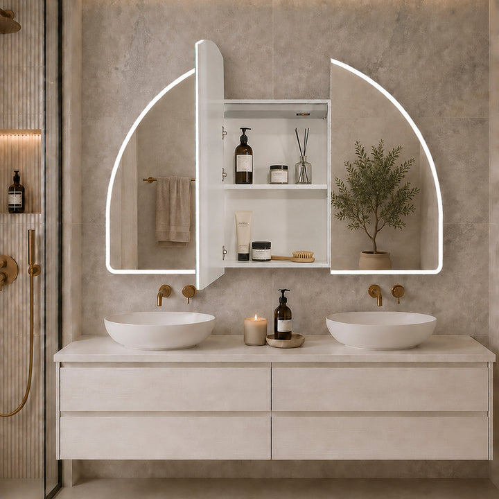 Arch LED mirror cabinet with illuminated edges and open doors revealing internal shelves above a double basin vanity with gold tapware.
