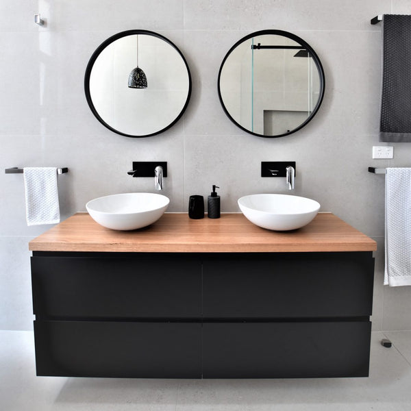 2 Deluxe 600mm Round Mirrors with Black Frame on a Limestone White Tile. Timber Bench tops on Black All-Drawer Vanities