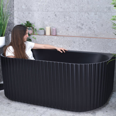 Agora Groove 1700mm back to wall bathtub in matte black, angled view with model